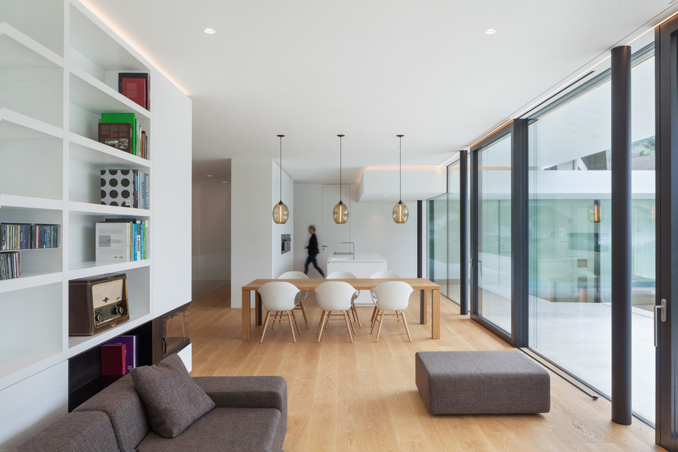 Cette image montre un salon minimaliste ouvert avec un mur blanc, parquet clair, une cheminée double-face, un manteau de cheminée en plâtre, une salle de réception et un sol beige.
