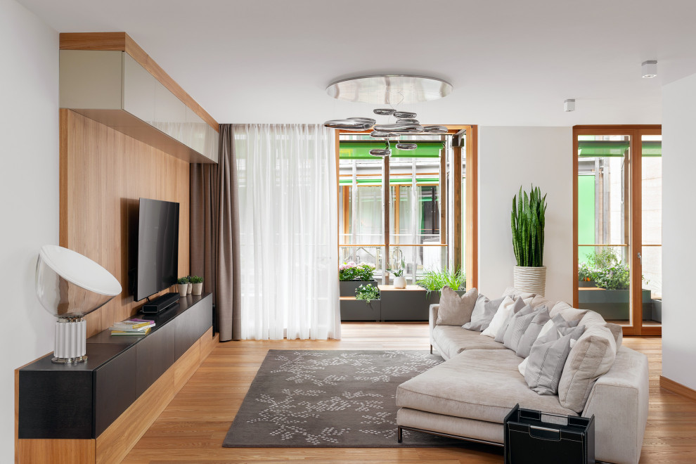 Imagen de salón abierto actual de tamaño medio con paredes blancas, pared multimedia y suelo beige