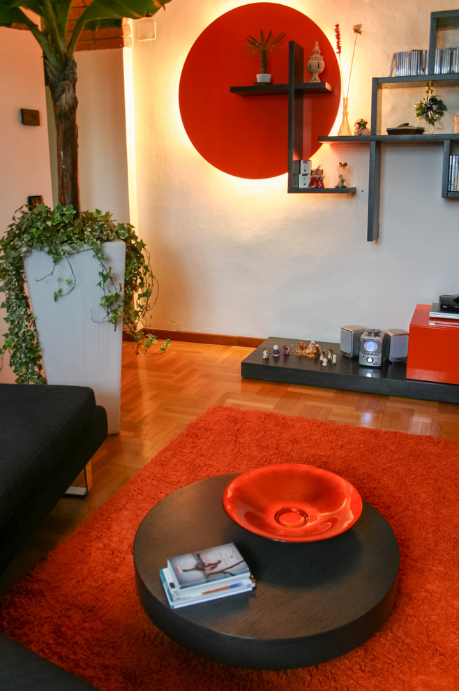 Idée de décoration pour un petit salon design fermé avec une bibliothèque ou un coin lecture, un mur orange, un téléviseur encastré et un sol en bois brun.