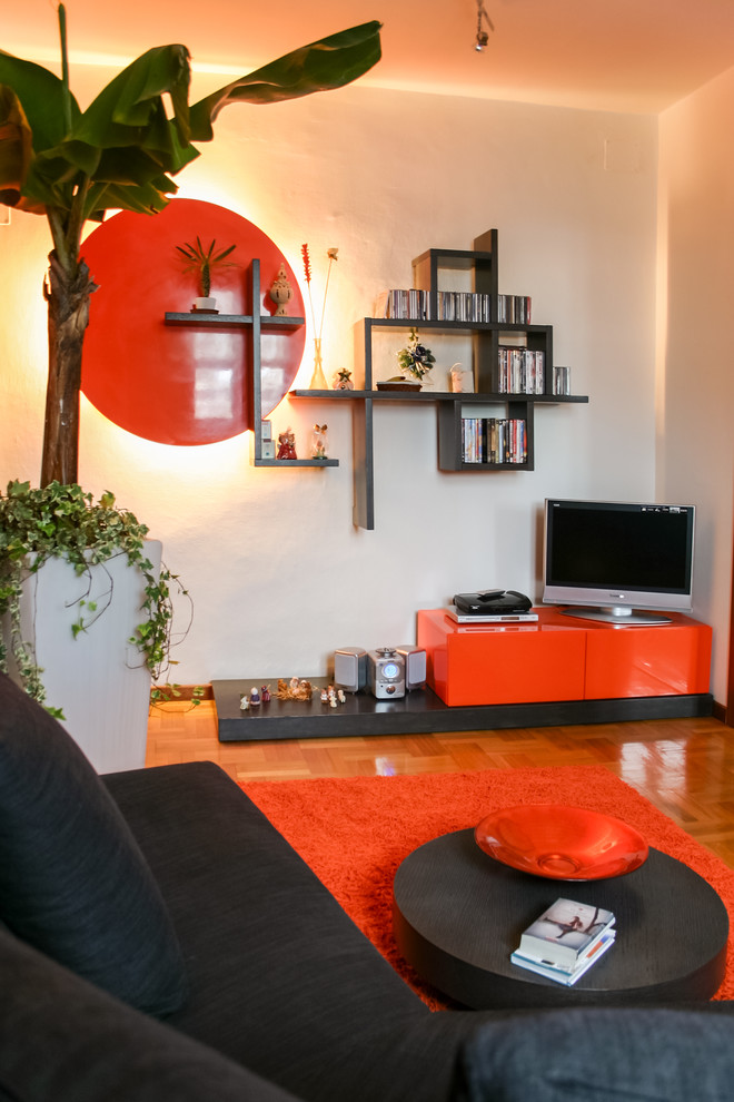 Foto di un piccolo soggiorno minimal chiuso con libreria, pareti arancioni, parete attrezzata e pavimento in legno massello medio