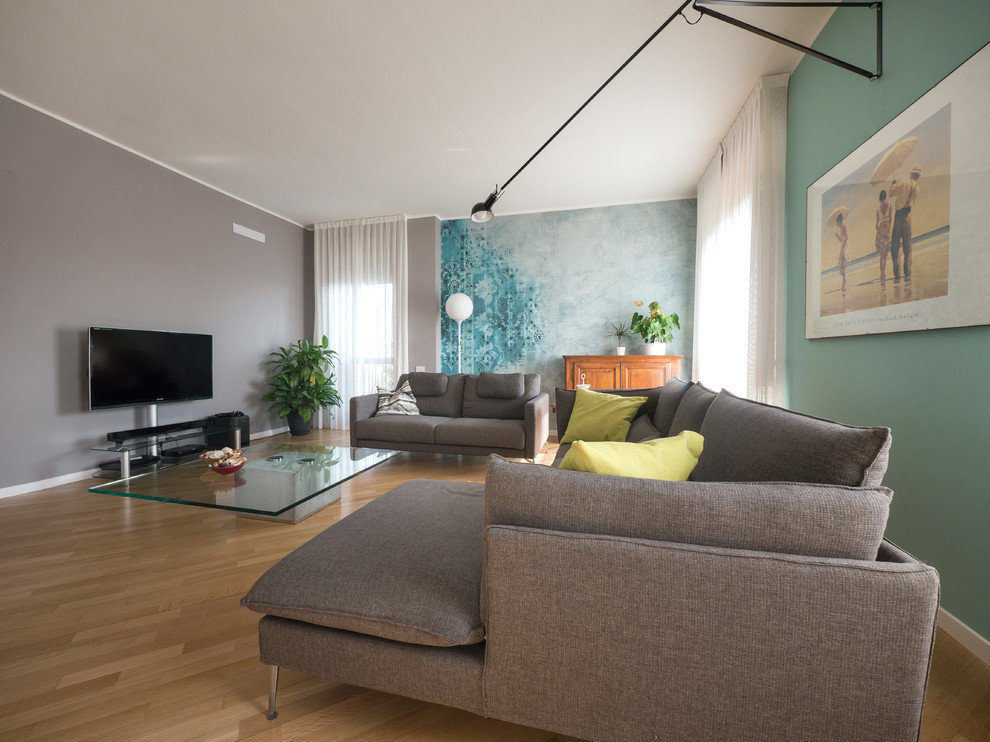 Diseño de salón para visitas abierto contemporáneo grande con paredes verdes, suelo de madera clara y televisor independiente
