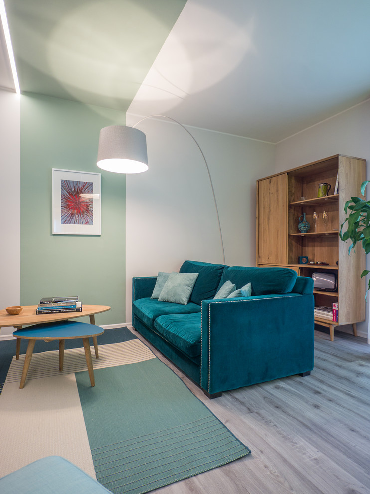 На фото: открытая гостиная комната среднего размера в современном стиле с с книжными шкафами и полками, зелеными стенами, полом из линолеума, мультимедийным центром и серым полом с