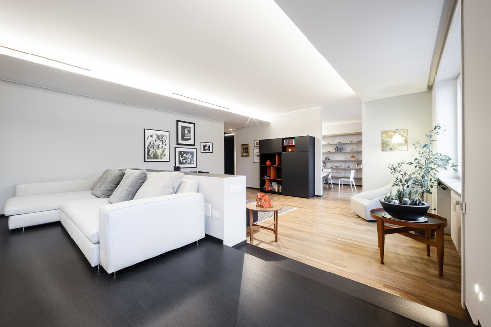 На фото: открытая гостиная комната среднего размера в современном стиле с белыми стенами, деревянным полом и черным полом