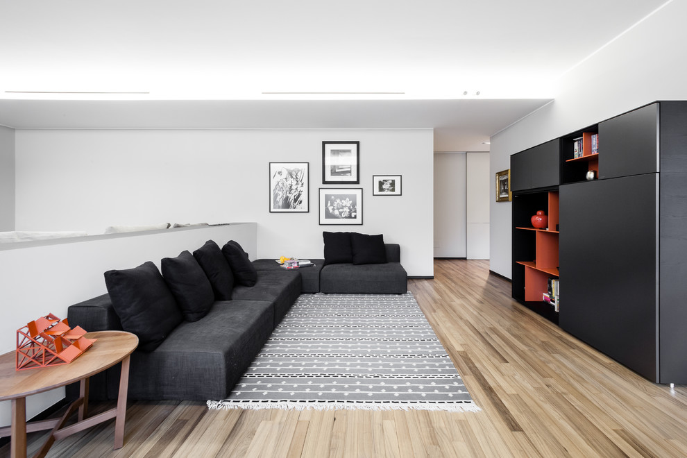 Diseño de biblioteca en casa abierta y gris y negra actual de tamaño medio con paredes blancas y suelo de madera clara