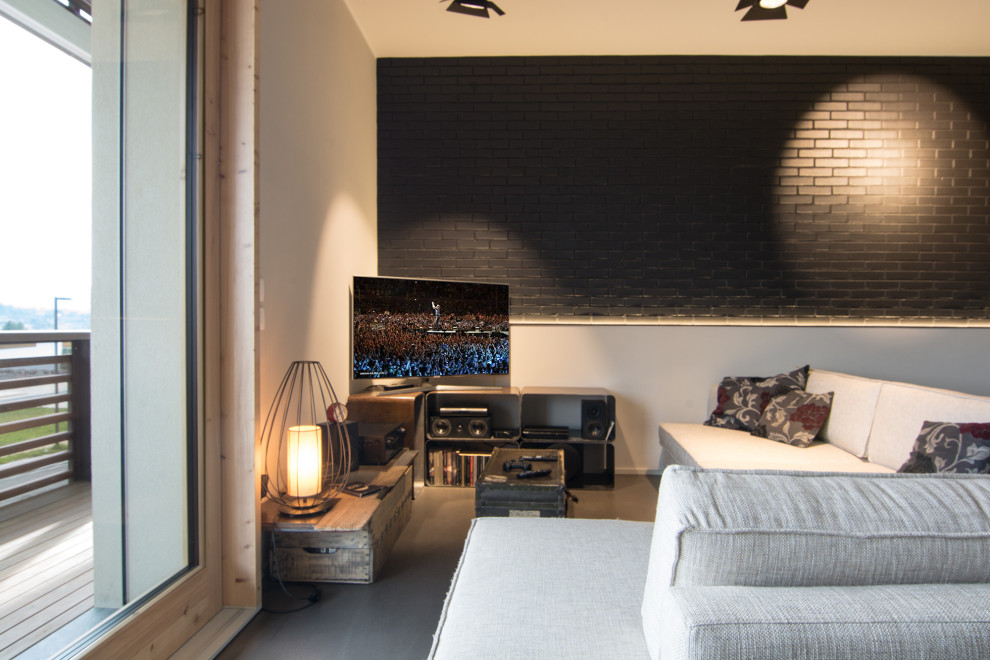 Idées déco pour une salle de séjour mansardée ou avec mezzanine industrielle de taille moyenne avec un mur gris, sol en béton ciré, un téléviseur encastré et un sol gris.