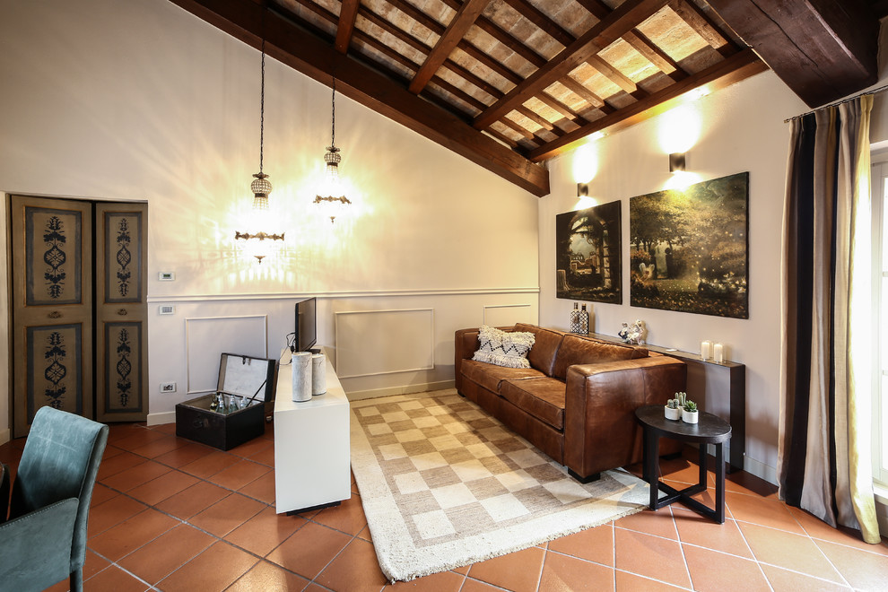 Пример оригинального дизайна: двухуровневая, парадная гостиная комната в средиземноморском стиле с отдельно стоящим телевизором, бежевыми стенами, полом из терракотовой плитки и коричневым полом