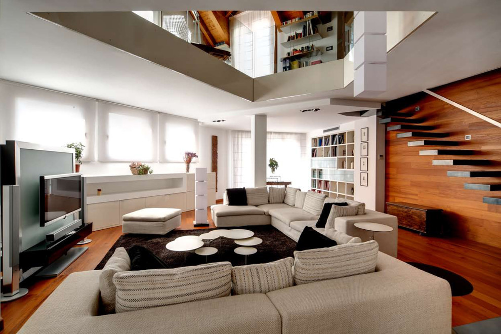 Diseño de salón abierto contemporáneo sin chimenea con paredes blancas, suelo de madera en tonos medios, televisor colgado en la pared y suelo marrón