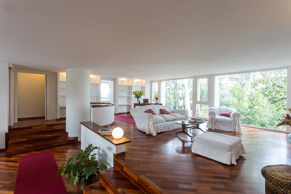 Aménagement d'un très grand salon classique ouvert avec un mur blanc et un sol en bois brun.