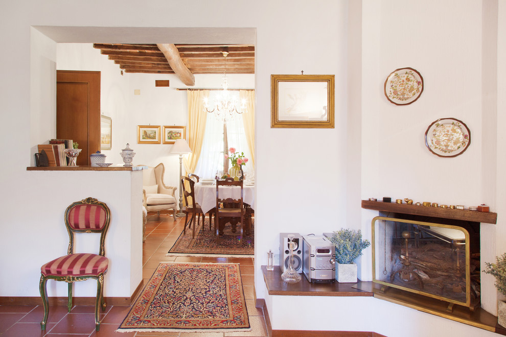 Immagine di un soggiorno chic con pareti bianche, pavimento in terracotta, camino classico e cornice del camino in intonaco