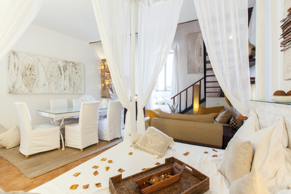 Cette image montre un salon méditerranéen de taille moyenne et ouvert avec un mur blanc, aucun téléviseur, un sol en carrelage de céramique et un sol marron.