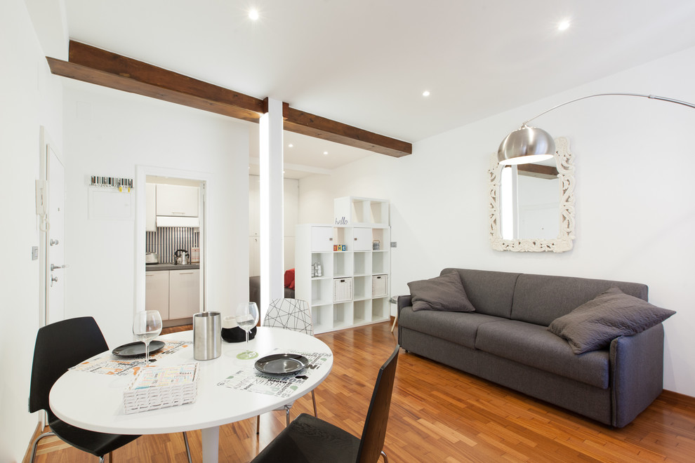 Imagen de salón abierto actual de tamaño medio con paredes blancas y suelo de madera en tonos medios