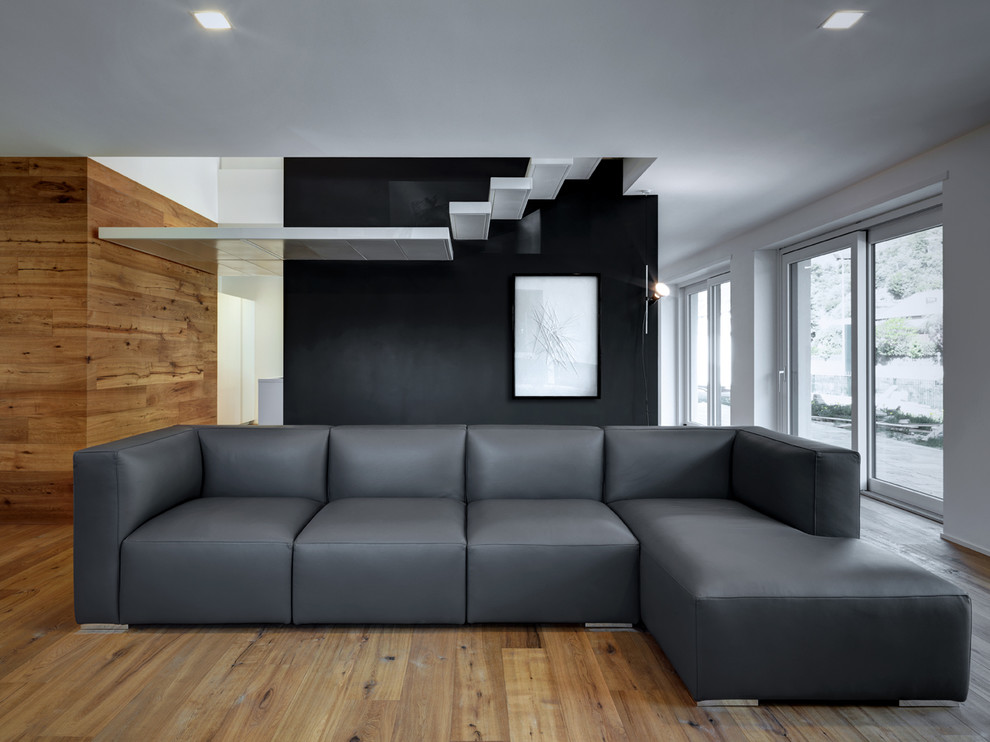 Bild på ett funkis vardagsrum, med svarta väggar och mellanmörkt trägolv