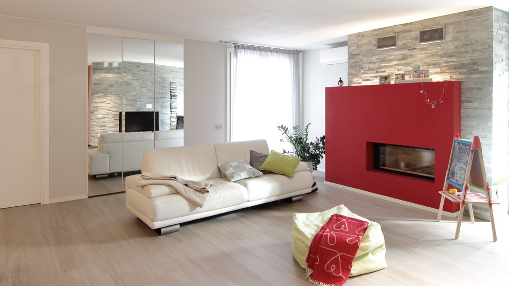 Modelo de sala de juegos en casa abierta industrial extra grande con paredes rojas, chimenea lineal y marco de chimenea de piedra