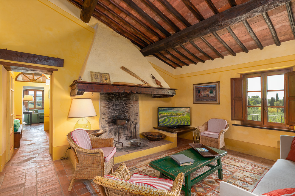 Idee per un soggiorno mediterraneo chiuso con pareti gialle, pavimento in terracotta, TV autoportante e pavimento arancione