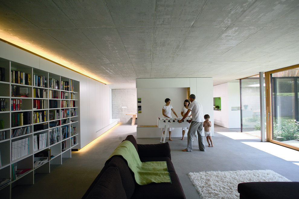 Idee per un ampio soggiorno design con libreria, pareti grigie e pavimento in cemento