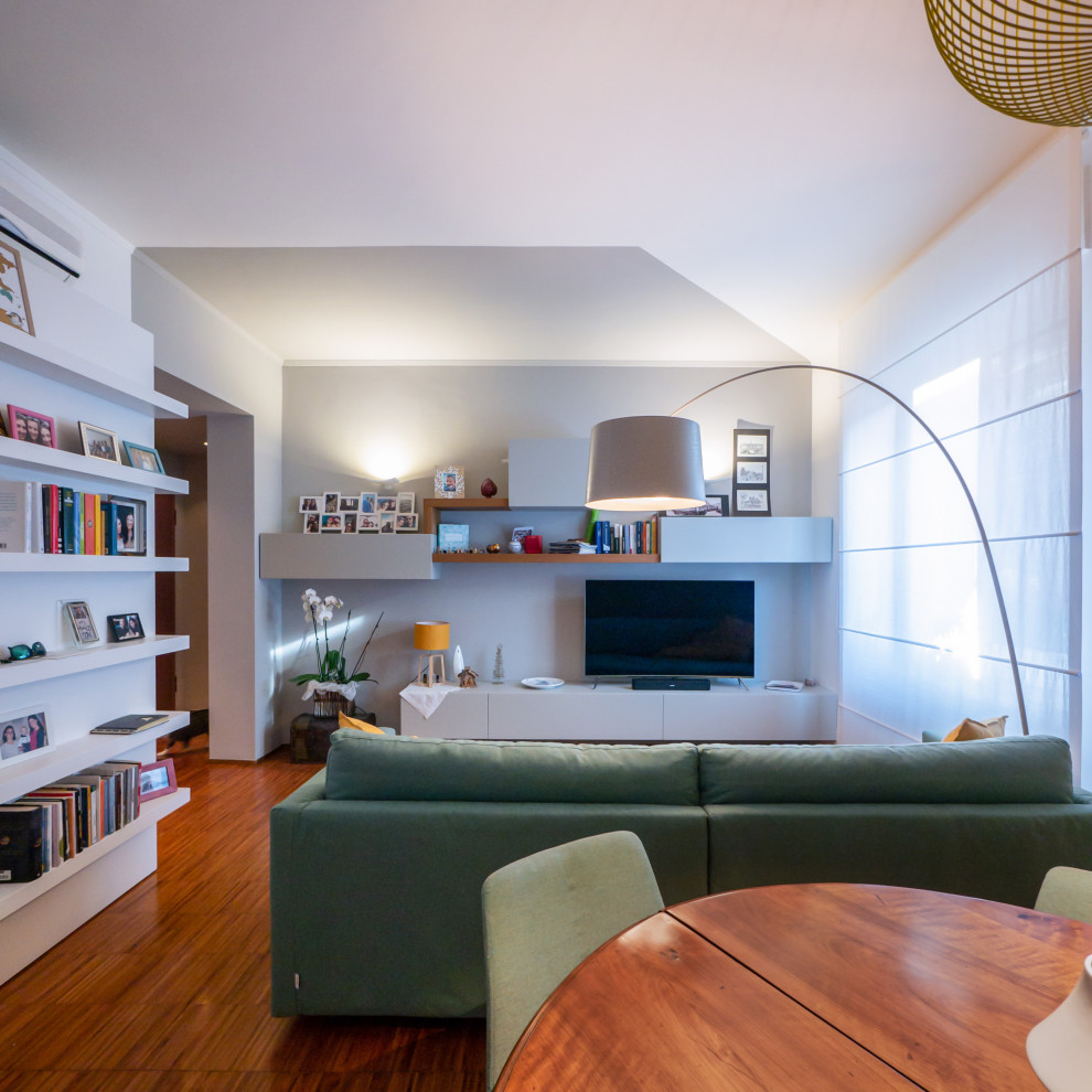 На фото: открытая гостиная комната в современном стиле с с книжными шкафами и полками, разноцветными стенами, темным паркетным полом и мультимедийным центром с