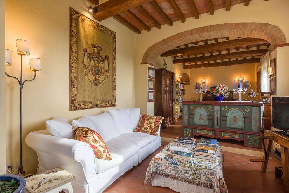 Immagine di un soggiorno mediterraneo con pareti beige, pavimento in terracotta, TV autoportante e pavimento rosso