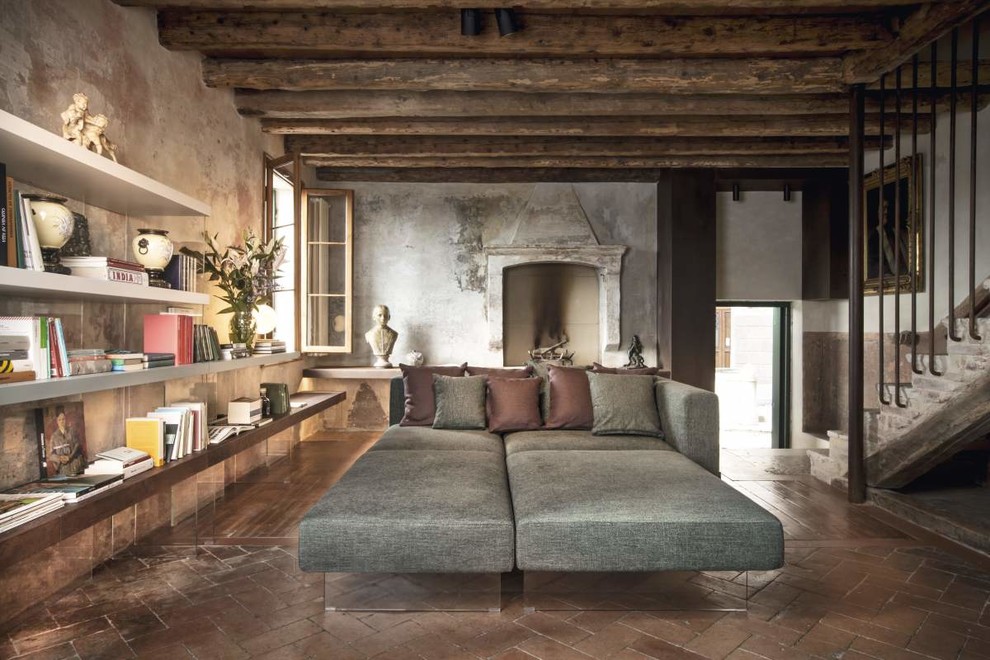 ヴェネツィアにある中くらいなインダストリアルスタイルのおしゃれなLDK (ライブラリー、標準型暖炉、グレーの壁、茶色い床) の写真