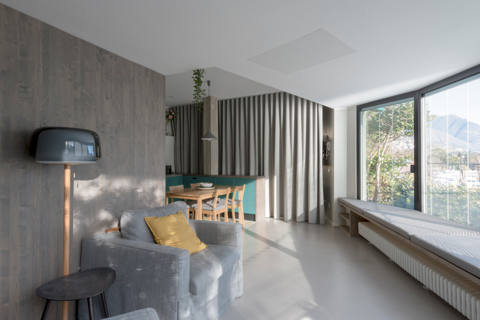Cette photo montre un petit salon tendance en bois ouvert avec un mur blanc, sol en béton ciré, un téléviseur fixé au mur et un sol gris.