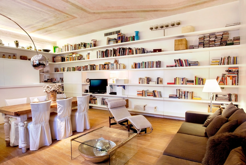 Стильный дизайн: большая изолированная гостиная комната в стиле фьюжн с с книжными шкафами и полками, белыми стенами, паркетным полом среднего тона и отдельно стоящим телевизором - последний тренд