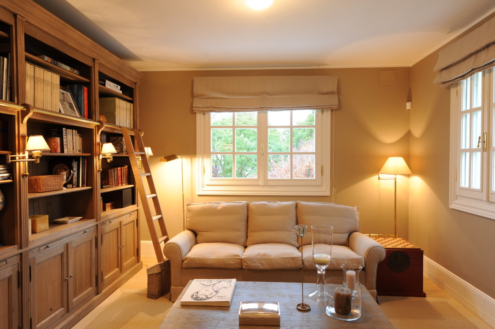 Foto di un piccolo soggiorno country con libreria, pareti beige, parquet chiaro e pavimento beige
