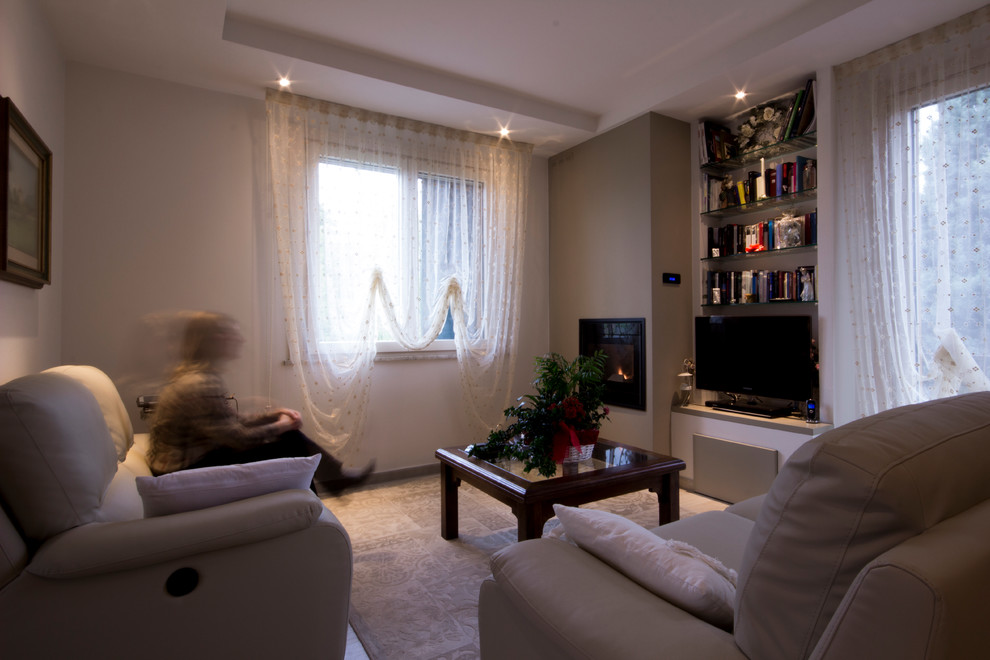 Diseño de sala de estar con biblioteca abierta romántica de tamaño medio con paredes beige, estufa de leña, marco de chimenea de yeso y televisor independiente