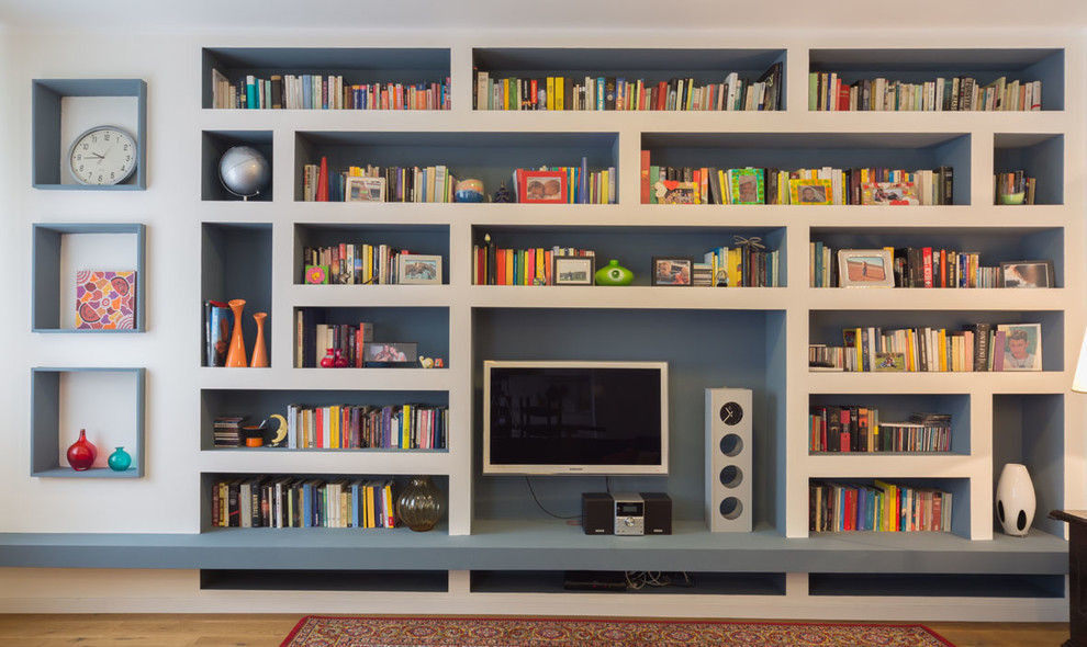 Пример оригинального дизайна: большая открытая гостиная комната в стиле модернизм с с книжными шкафами и полками, белыми стенами, паркетным полом среднего тона, телевизором на стене и коричневым полом