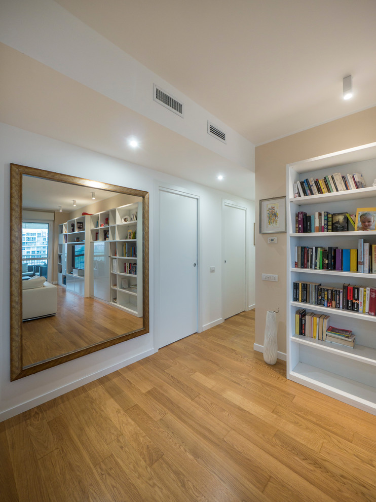 Imagen de biblioteca en casa abierta contemporánea grande con paredes rosas, suelo de madera clara y pared multimedia