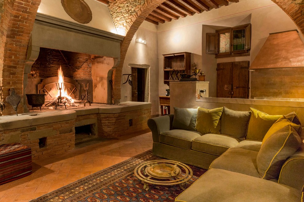 Foto de sala de estar mediterránea con suelo de ladrillo, todas las chimeneas y marco de chimenea de piedra