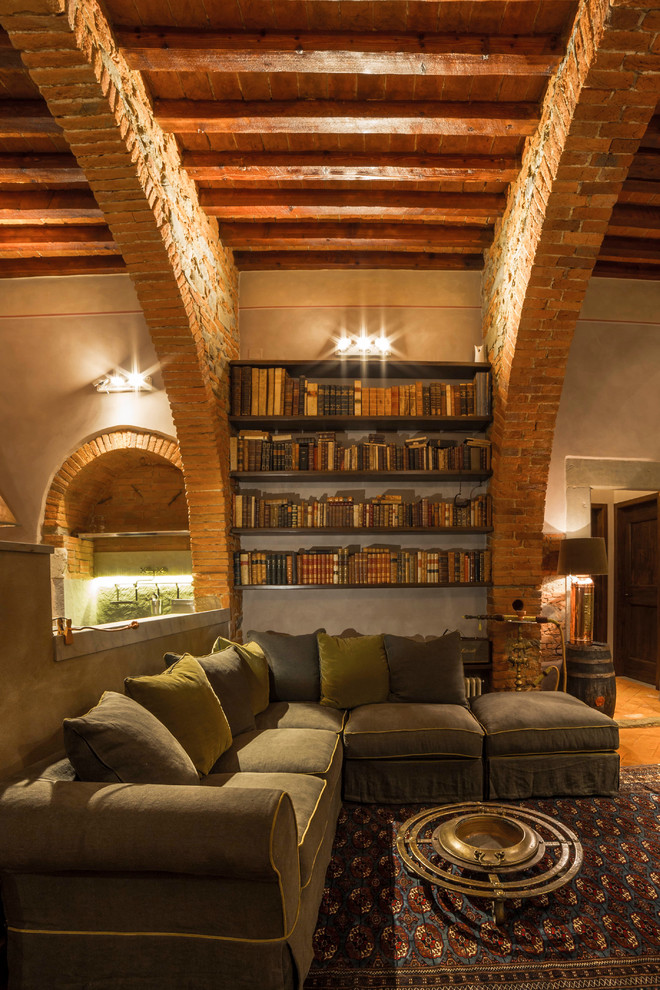 Ejemplo de sala de estar mediterránea con suelo de ladrillo y marco de chimenea de piedra