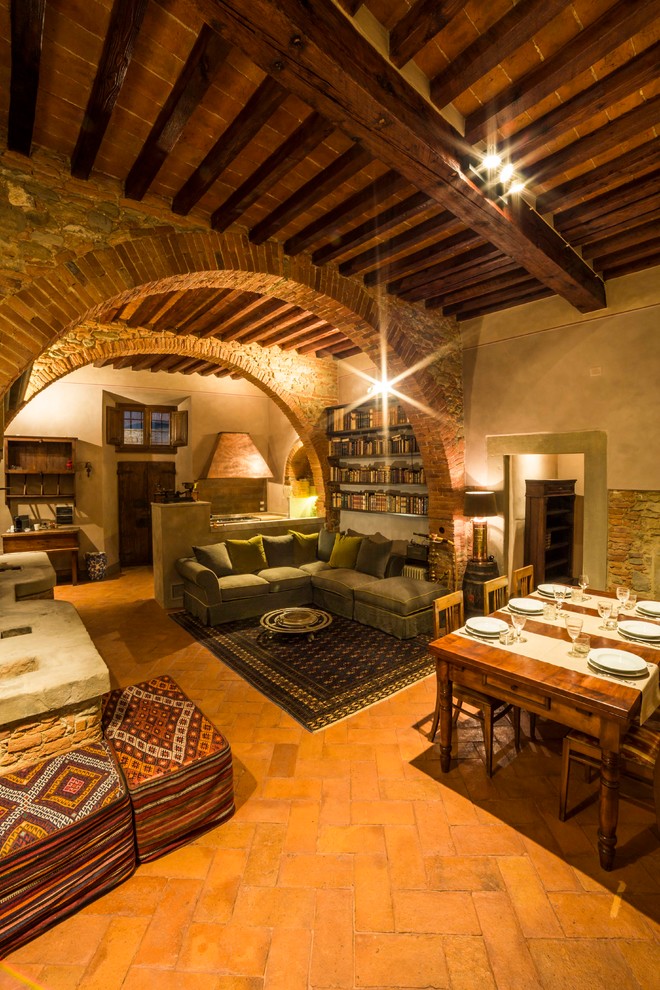 На фото: гостиная комната в средиземноморском стиле с кирпичным полом и фасадом камина из камня