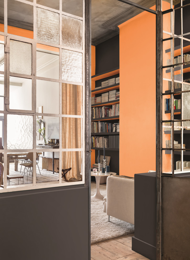 Foto di un soggiorno industriale con libreria e pareti arancioni