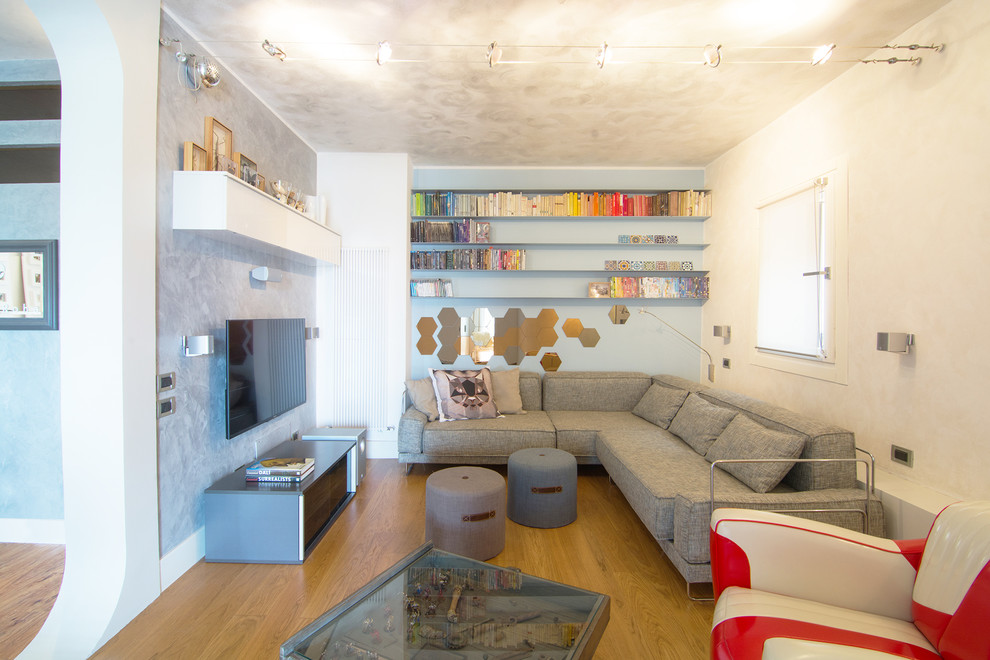 Foto på ett litet eklektiskt loftrum, med ett bibliotek, flerfärgade väggar, ljust trägolv och en väggmonterad TV
