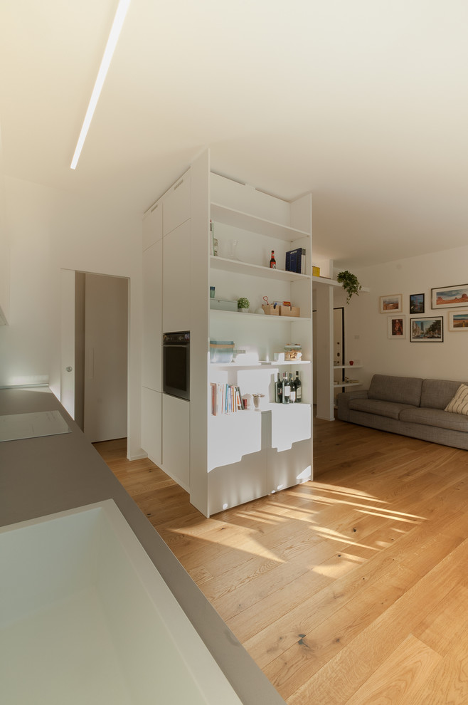 Foto de biblioteca en casa abierta contemporánea de tamaño medio con paredes blancas, suelo de madera clara, pared multimedia y suelo beige
