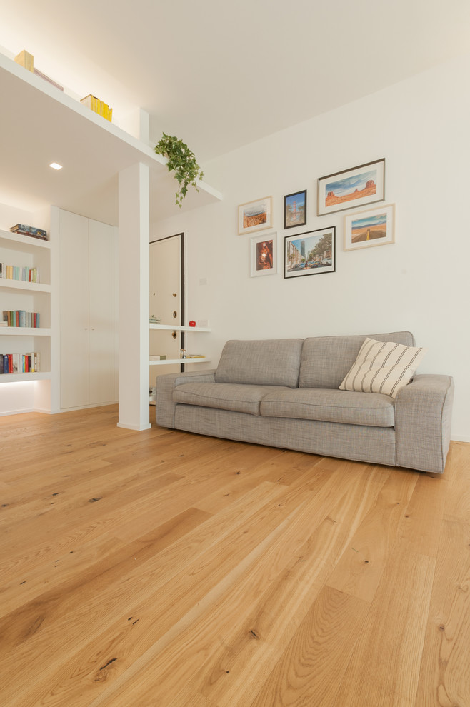 Esempio di un soggiorno minimal di medie dimensioni e aperto con libreria, pareti grigie, parquet chiaro, parete attrezzata e pavimento beige