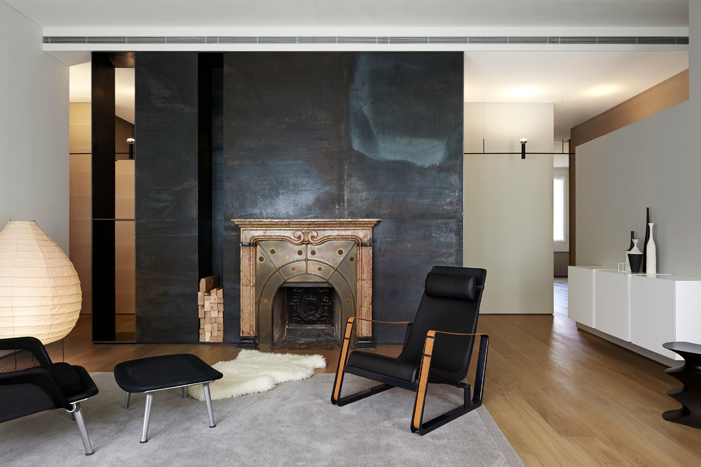 Idee per un soggiorno minimal con pareti nere, parquet chiaro, camino classico e cornice del camino in pietra