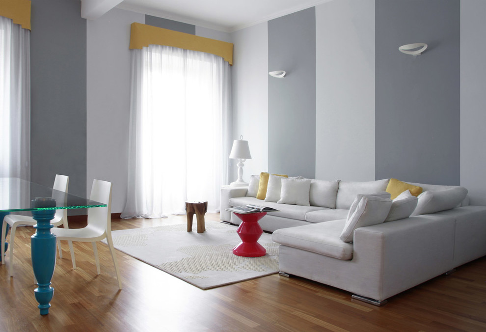 Modelo de salón para visitas abierto actual grande con paredes grises y suelo de madera en tonos medios