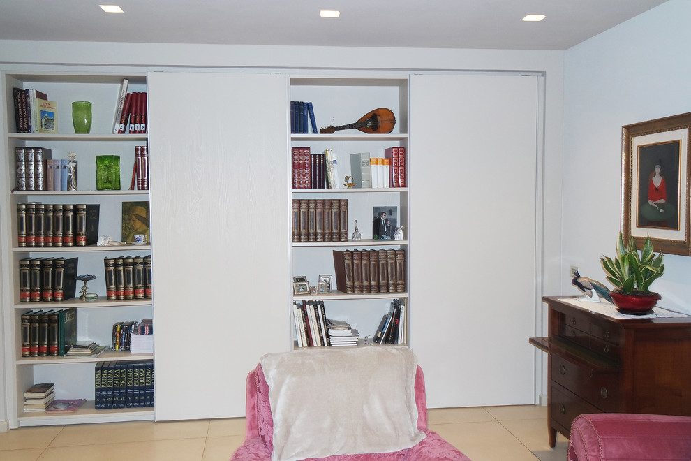 Imagen de sala de estar con biblioteca abierta actual de tamaño medio sin chimenea con paredes multicolor, suelo de baldosas de cerámica, televisor independiente y suelo beige
