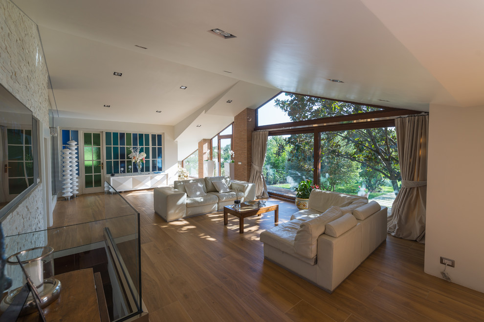 Immagine di un grande soggiorno contemporaneo aperto con pareti bianche, pavimento in gres porcellanato, TV a parete e pavimento marrone
