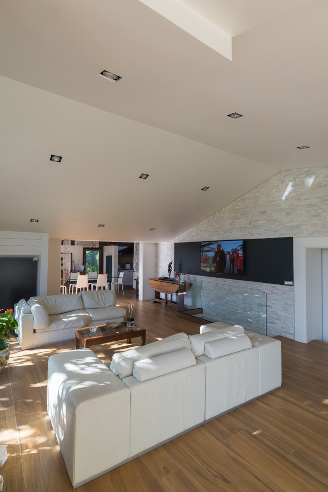 Esempio di un grande soggiorno minimal aperto con pareti bianche, pavimento in gres porcellanato, TV a parete e pavimento marrone
