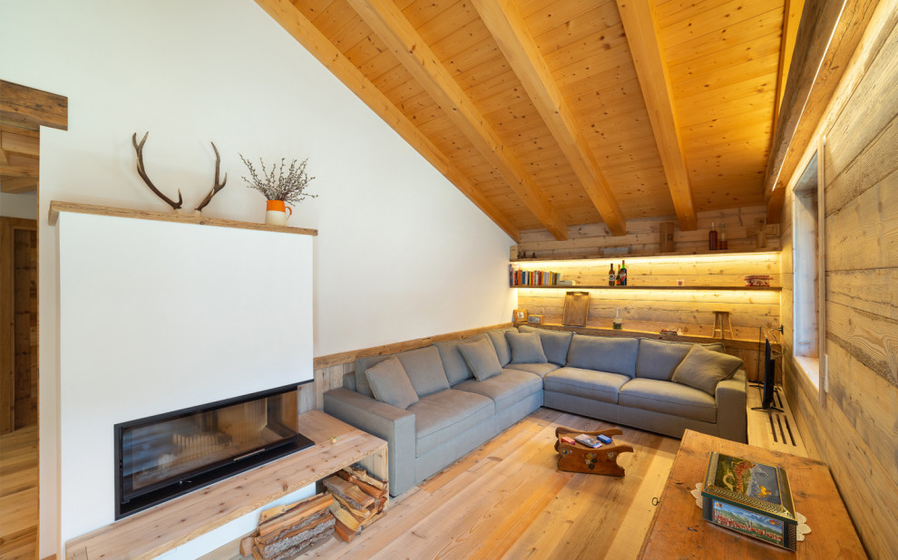Immagine di un soggiorno stile rurale chiuso con pareti bianche, parquet chiaro, camino bifacciale, nessuna TV, travi a vista, soffitto in legno e soffitto a volta