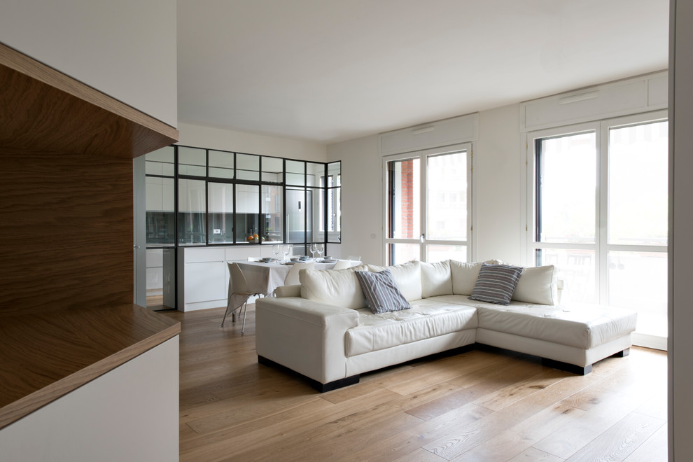 Immagine di un grande soggiorno design aperto con pareti bianche, parquet chiaro, TV a parete e pavimento beige