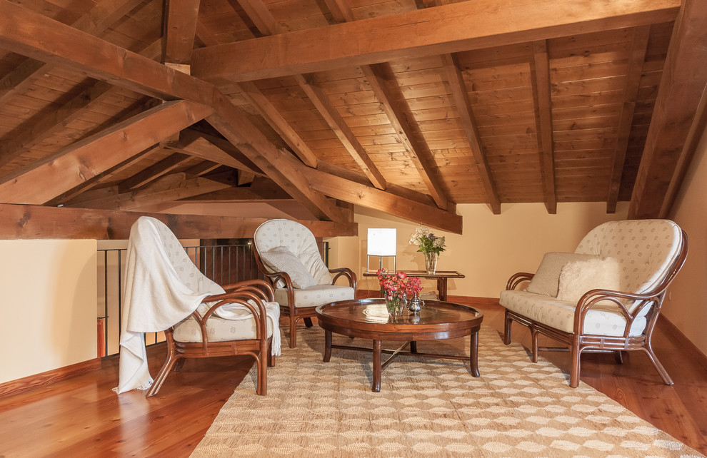 Exemple d'un salon mansardé ou avec mezzanine méditerranéen avec une salle de réception, un mur beige, un sol en bois brun et un sol marron.