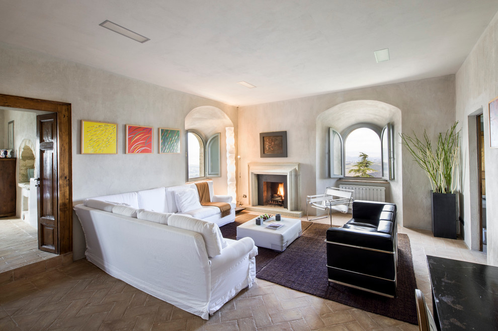 Стильный дизайн: изолированная гостиная комната в средиземноморском стиле с белыми стенами, кирпичным полом, стандартным камином и фасадом камина из камня - последний тренд