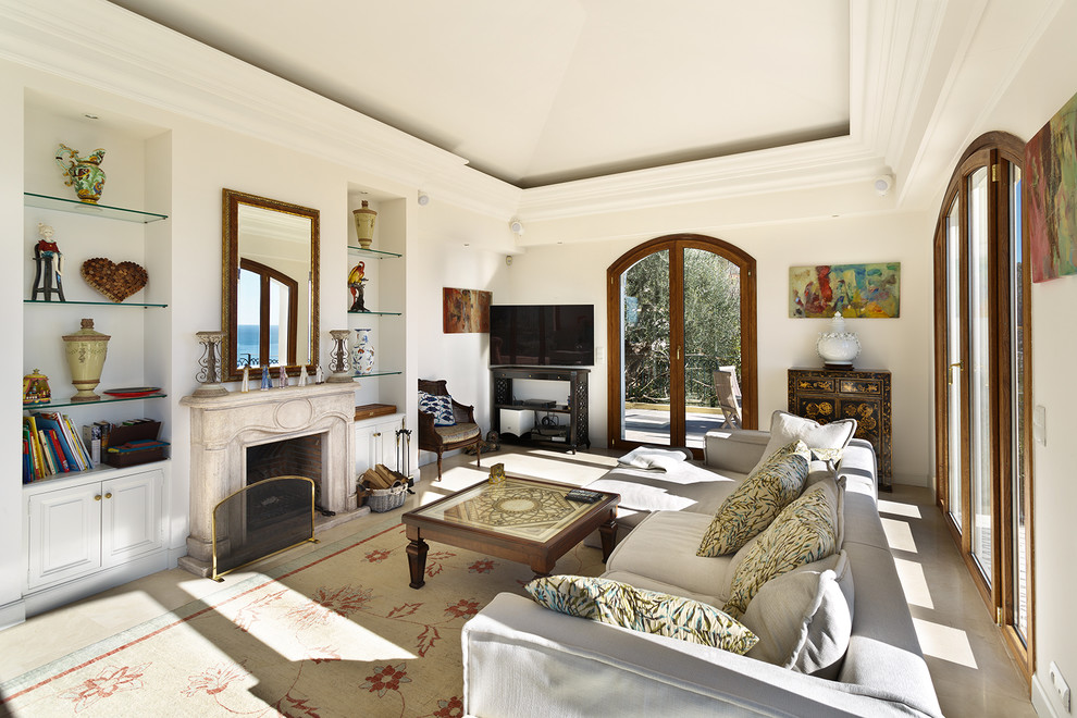 This is an example of a mediterranean games room with beige walls, a standard fireplace, a freestanding tv and beige floors.