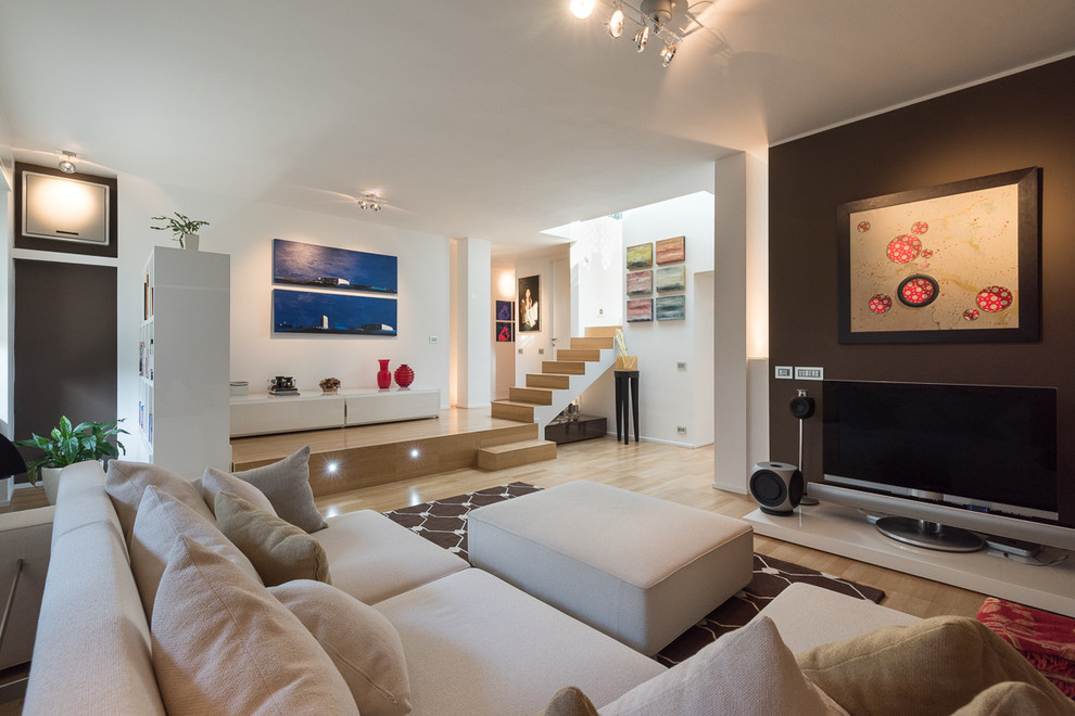 Large contemporary open plan living room in Milan with a music area, multi-coloured walls, light hardwood flooring and a freestanding tv.