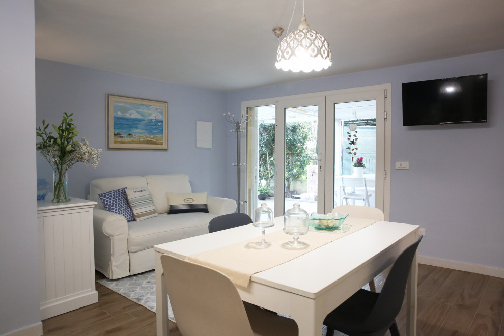 Foto di un piccolo soggiorno stile marinaro aperto con pareti blu, pavimento in gres porcellanato e TV a parete