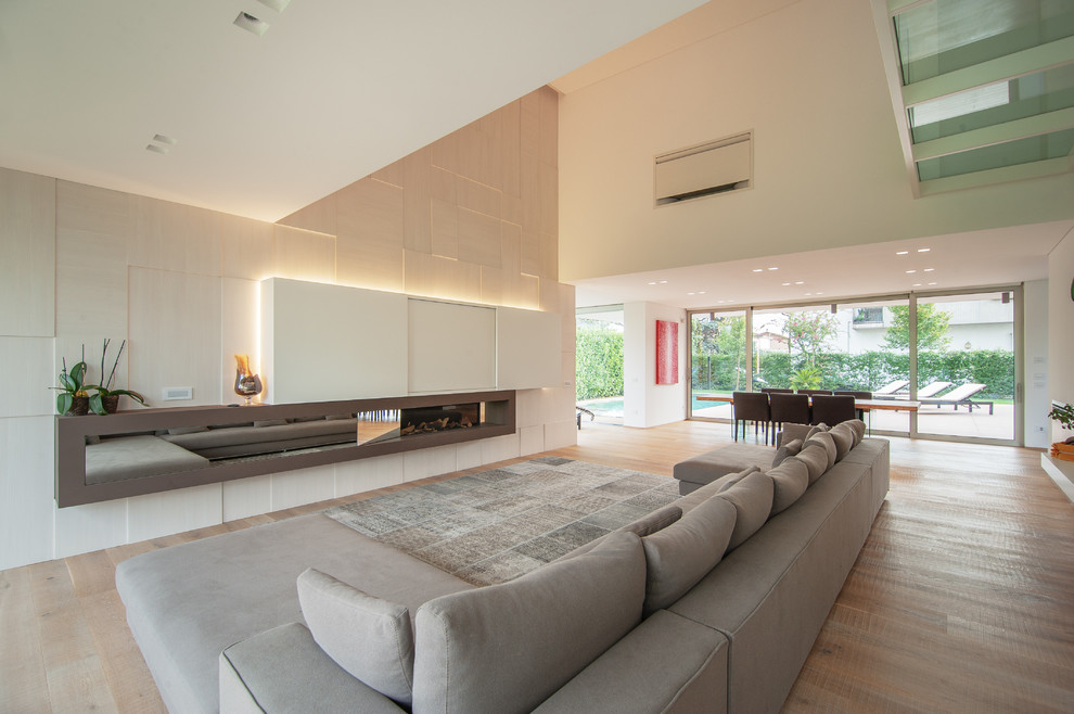 Imagen de salón abierto moderno grande con paredes beige y suelo de madera clara