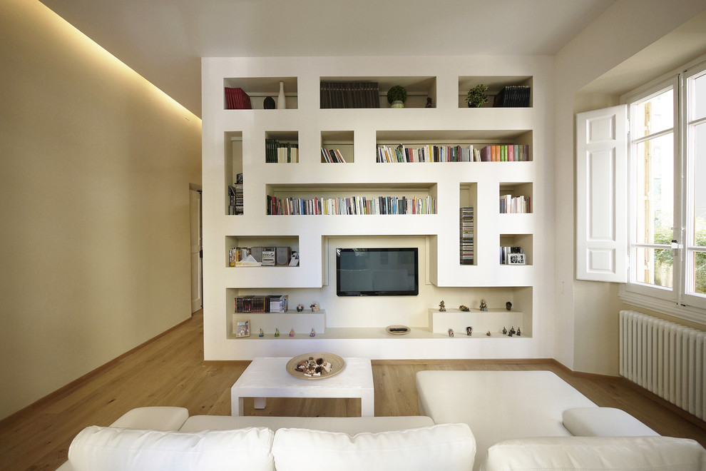 Immagine di un soggiorno minimalista di medie dimensioni e aperto con libreria, pareti bianche, pavimento in legno massello medio e TV a parete