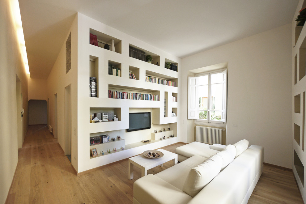 Esempio di un soggiorno minimalista di medie dimensioni e aperto con libreria, pareti bianche, pavimento in legno massello medio, TV a parete e pavimento marrone